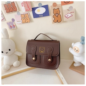 Detail of vintage brown PU leather kids backpack with golden bear embroidery decoration