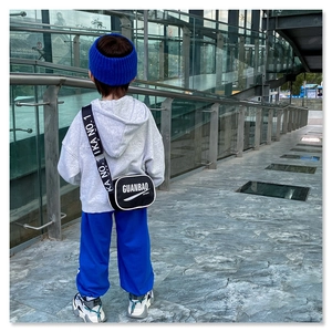 Detailed view of black kids sporty crossbody bag with letter print strap and grey hoodie