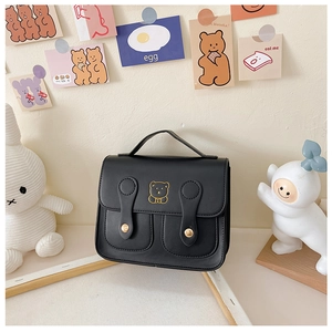 Detail of black PU leather kids backpack featuring a gold bear motif and buckle straps