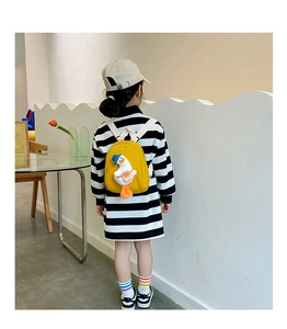 Rear view of a child wearing the yellow duck canvas backpack in a cozy indoor setting