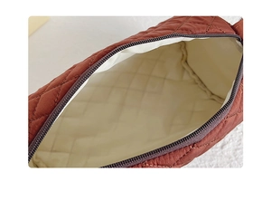 Detail of quilted brown canvas bucket bag showing zipper closure and beige inner lining