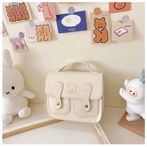Detail of cream PU leather kids backpack with cute gold-line bear motif and metal buckles