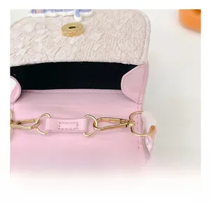 Détails des ferrures dorées et de la dentelle blanche sur un sac rose pour filles