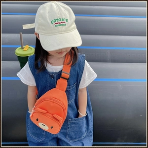 Détail d'un enfant portant un sac de poitrine orange en toile avec un motif d'ours