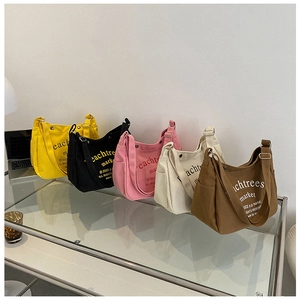 Detailed arrangement of canvas crossbody bags in five colors on a glass table