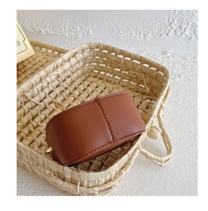 Detailed view of the brown leather mini bag with vertical stitching in a woven basket