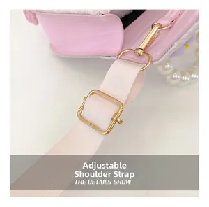 Détail du sac rose pour enfant avec poignée en perles, fermoirs dorés et sangle tissée