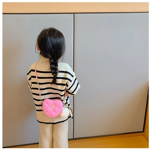 Detail of pink heart-shaped crossbody bag with gold floral clasp and chain strap for girls