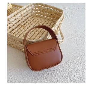 Detailed view of a mini brown leather handbag for girls with fine stitching and top handle