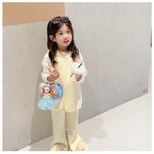Detail of blue sequin kids bag with doll decor and pearl handle on yellow outfit