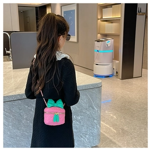Pink quilted round handbag for girls with a green bow and chain strap being worn