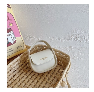 Detailed macro of a cream mini PU leather girl handbag with gold metal clasp