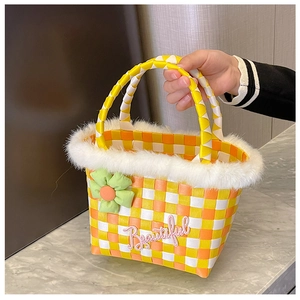 Detail of checkered woven handbag with white faux fur trim and green fabric flower