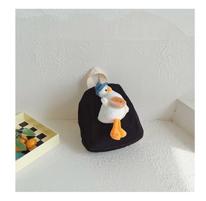 Close-up of black canvas backpack with a plush white duck wearing a blue sun hat