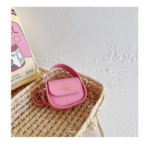 Close-up of a pink mini leather girl's handbag with gold fashion lettering in a woven basket
