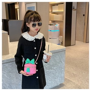 Pink quilted girl's crossbody bag with green bow and chain strap on a child model