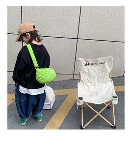 Close-up of vibrant green quilted cylindrical crossbody bag for kids in outdoor setting