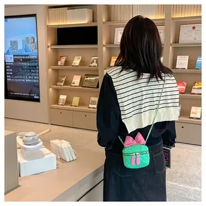 Detail of mint green quilted mini bag with oversized pink bow and woven chain strap