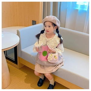 Petite fille portant un béret en peluche beige et un gilet à fleurs avec un col en dentelle