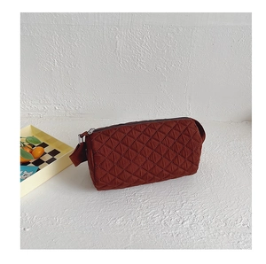 Close-up of quilted brick red canvas bucket bag showing diamond stitching and zipper detail