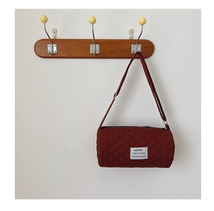 Detail of reddish-brown quilted bucket bag with diamond stitching on a wooden wall hook