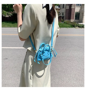 Close-up of bright blue mini shell bag with drawstring detail on a model in street style