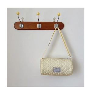 Detail of cream quilted cylinder bag with fashion label and adjustable shoulder strap