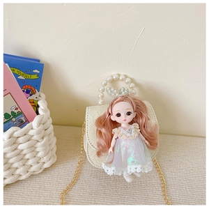 Detail of white mini crossbody bag featuring a pink doll ornament and pearl handle