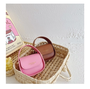 Detailed close-up of pink and brown mini saddle bags with gold lettering in a basket