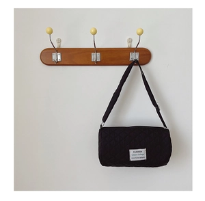 Detail of black quilted cylindrical crossbody bag with adjustable strap and fashion label