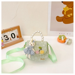 Détail du sac fille vert clair avec lapin en peluche, poignée perle et motif floral