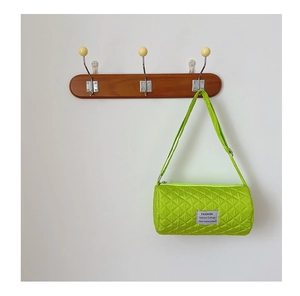 Detail of neon green quilted nylon bucket bag hanging on a wooden wall hook