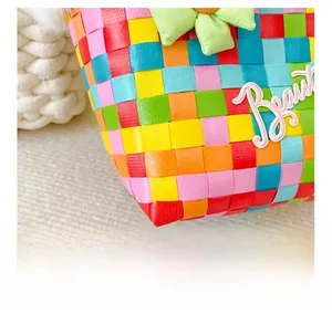 Close-up of colorful woven grid bag featuring pink 'Beautiful' embroidery and 3D floral detail