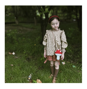 Outdoor vintage style showcase of a hand-knitted mushroom crossbody bag for young girls