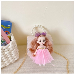 Detail of pink mini bag with pearl handle, golden chain, and cute doll decoration