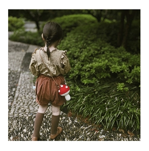 Detailed back view of a child wearing a handmade crochet red mushroom crossbody bag