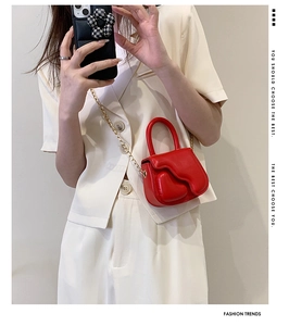 Detail of red wavy mini handbag with gold chain strap and elegant top handle