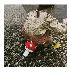 Detail of a handmade crochet mushroom bag with red polka dots on a little girl