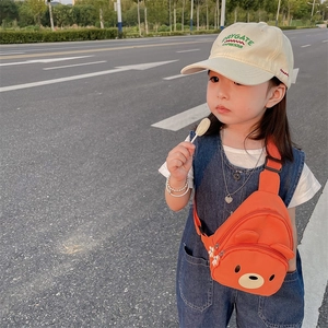 Sac de poitrine enfant orange avec ours mignon, porté par une petite fille