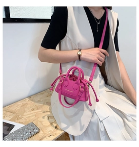 Detail of magenta mini shell bag showing the drawstring closure and gold fashion lettering