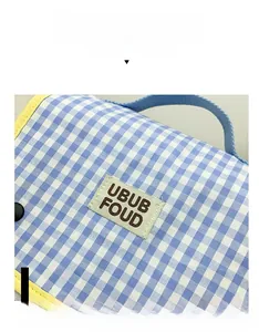 Close-up of blue and white checkered canvas school bag with yellow trim and UBUB label