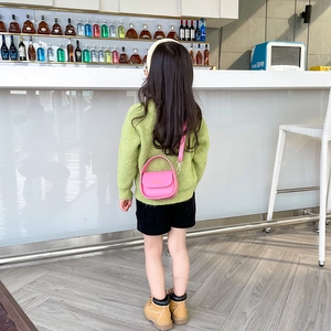 Pink mini crossbody bag for girls with top handle and strap shown on a child model
