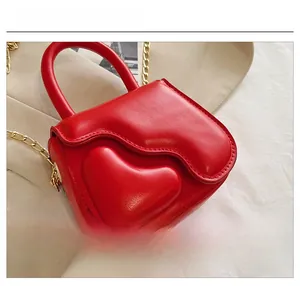 Detailed close-up of a red heart-shaped mini bag with gold chain and fine stitching