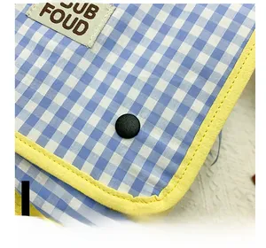 Close-up of blue checkered canvas kids backpack with yellow piping and snap button
