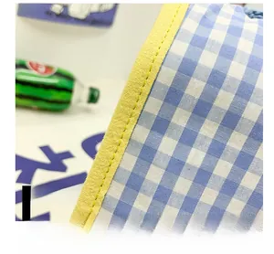 Detailed close-up of blue gingham fabric with reinforced yellow stitched edge finish