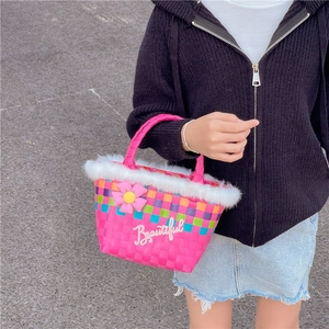 Pink woven handbag for girls with white faux fur trim and flower detail held by a model