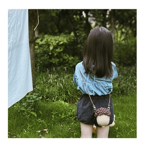 Detail of handmade crochet acorn crossbody bag with natural woven texture for little girls