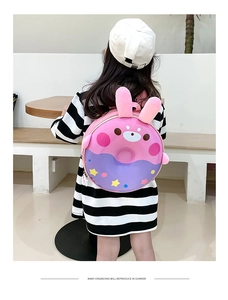 Vue arrière d'un enfant portant un sac à dos lapin violet et rose en forme de donut