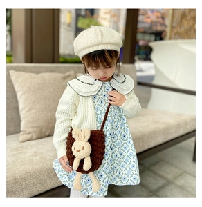 Détail d'un sac en tricot marron pour enfant avec lapin en peluche et robe à fleurs