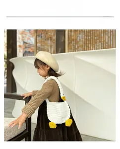 Close-up of a white knitted goose-shaped handbag for kids with yellow duck web feet